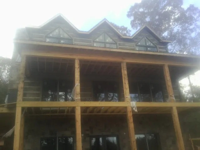 Dormers and porch framing on a large log home under construction — Roof Coating work by our crew in San Antonio