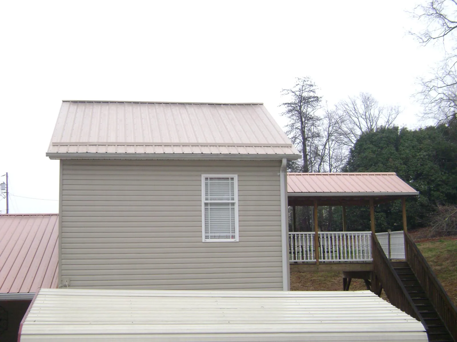 Tan metal roofs on a two story addition and attached porch, from a Roof Replacement job in San Antonio