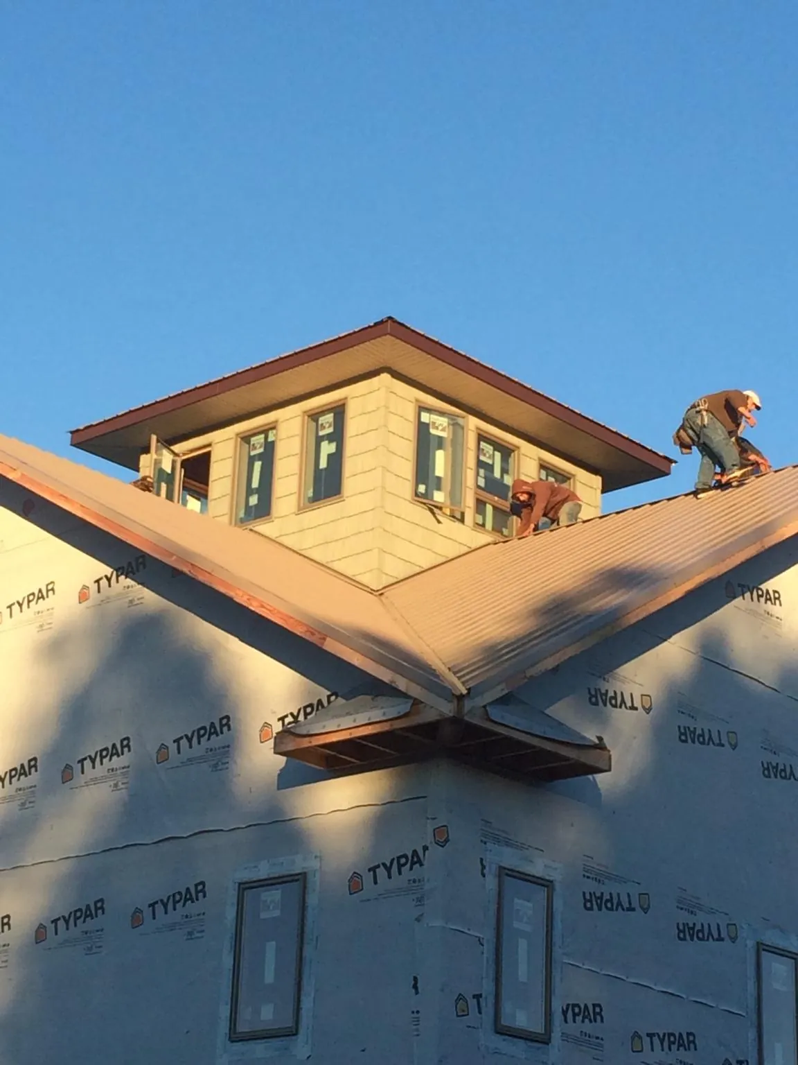 Roofers working around a rooftop cupola on a new metal roof at sunset — Roof Waterproofing in San Antonio by Roofing Brothers